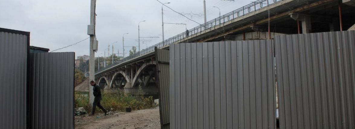 Поставили паркан і повісили риштування. Що відбувається під Київським мостом?